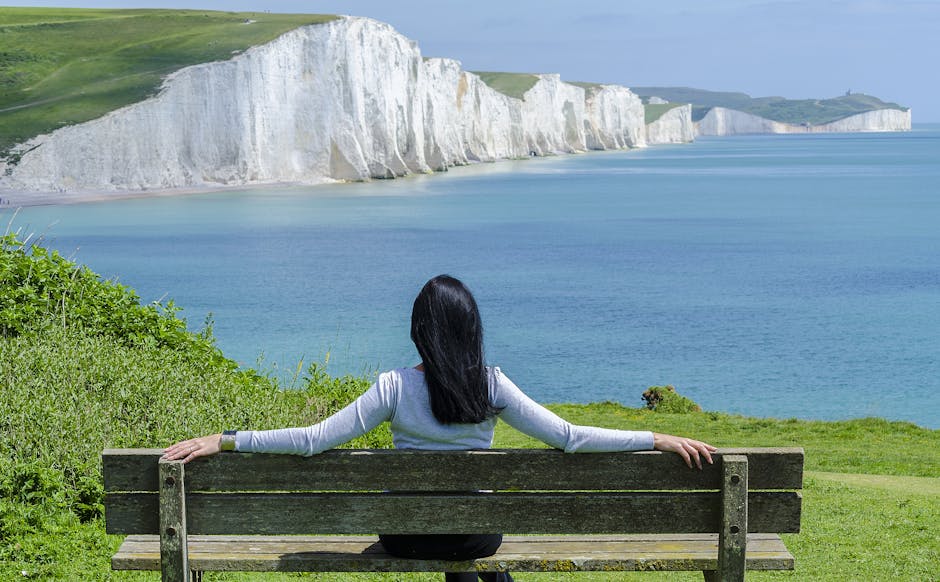 A woman relaxes on a bench, admiring the scenic cliffs and ocean view.